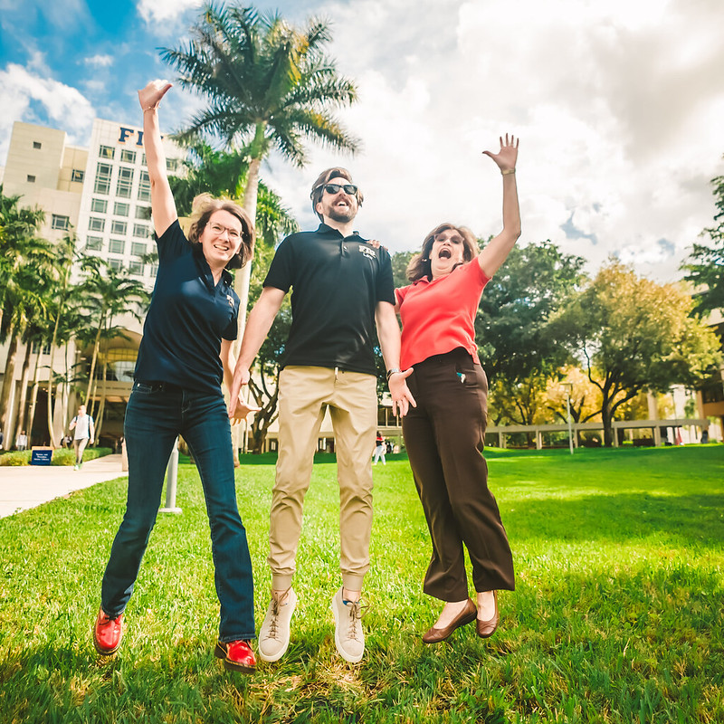 Three faculty and staff jumping in the air